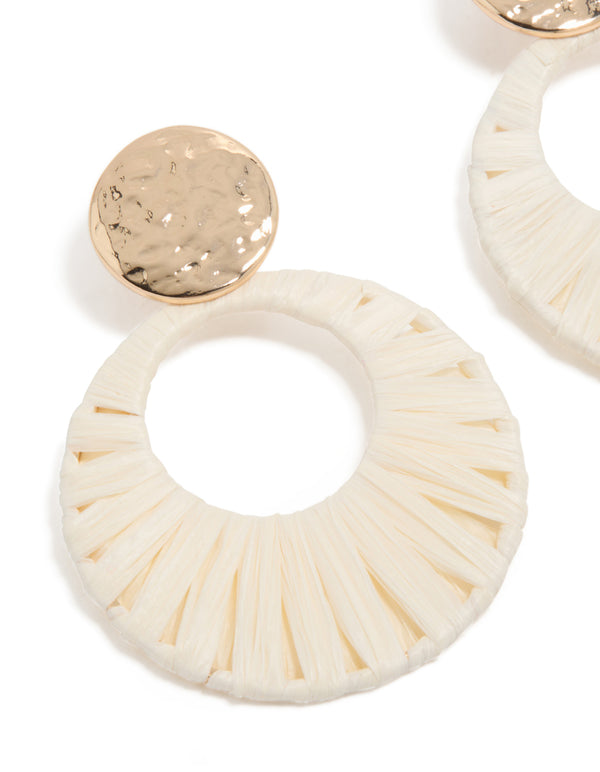 Featuring ivory raffia paper circle drops with hammered gold stud detail, statement earrings close up view