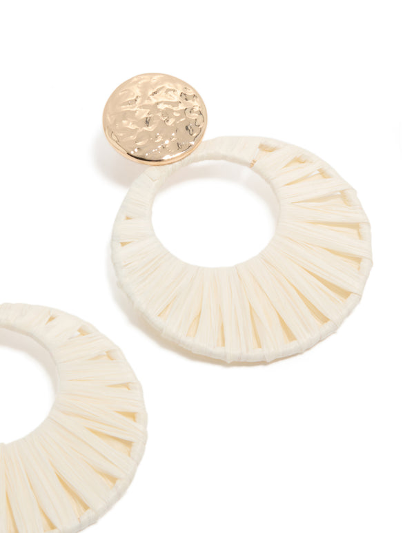 Highlighting the textured surface and construction of white raffia paper and hammered gold statement drop earrings post detail view