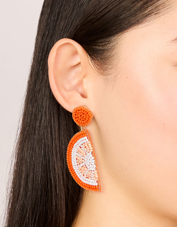 Crafted from beads featuring fruit detailing in orange white and peachpuff statement drop earrings on ear view