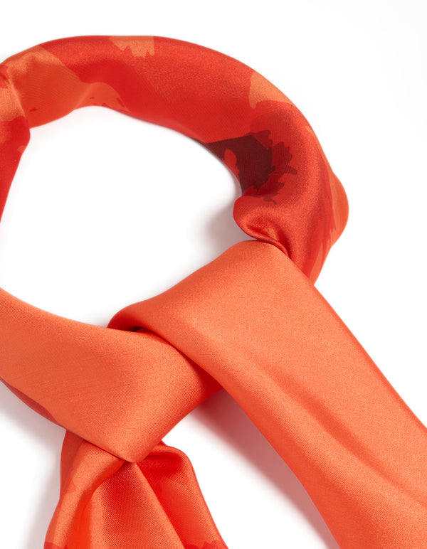 Highlighting an orange fabric scarf with double hibiscus floral print in coral, tomato, and dark orange shades, detail view