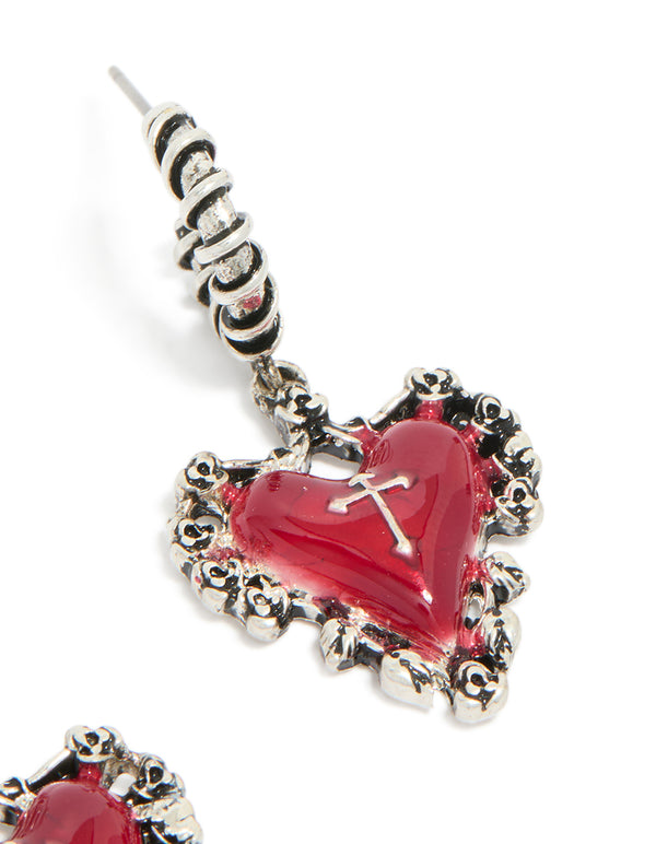 Capturing ornate detailing of statement huggie earrings with crimson heart and gothic cross in silver post detail view