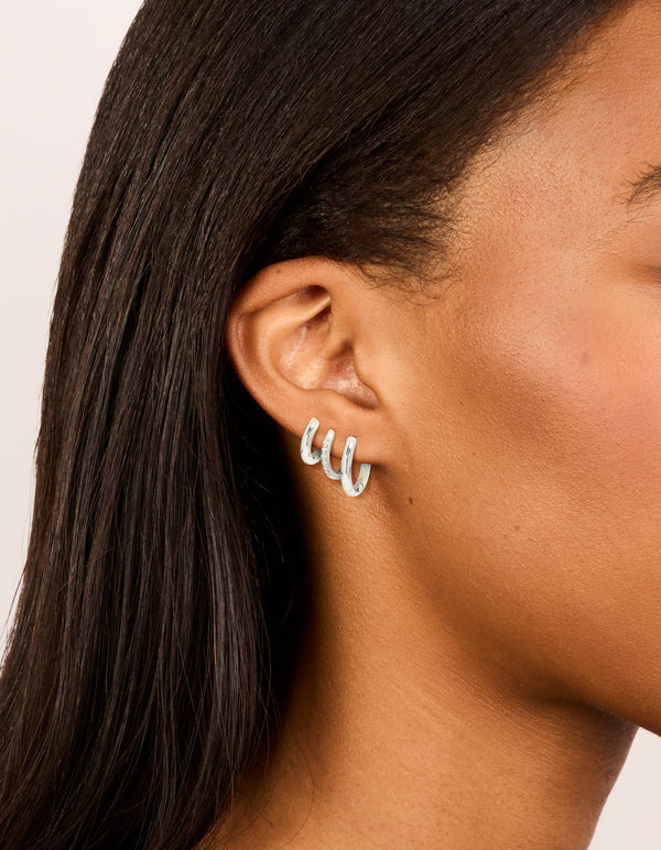 Showcasing waterproof stainless steel cubic zirconia essential stacking huggie earrings in a 3-pack with crystal and hoop closure, silver on ear view