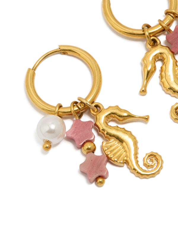 Showcasing waterproof gold plated stainless steel seahorse pearl charm huggie earrings with ocean celestial elements featuring in light pink and white close up view