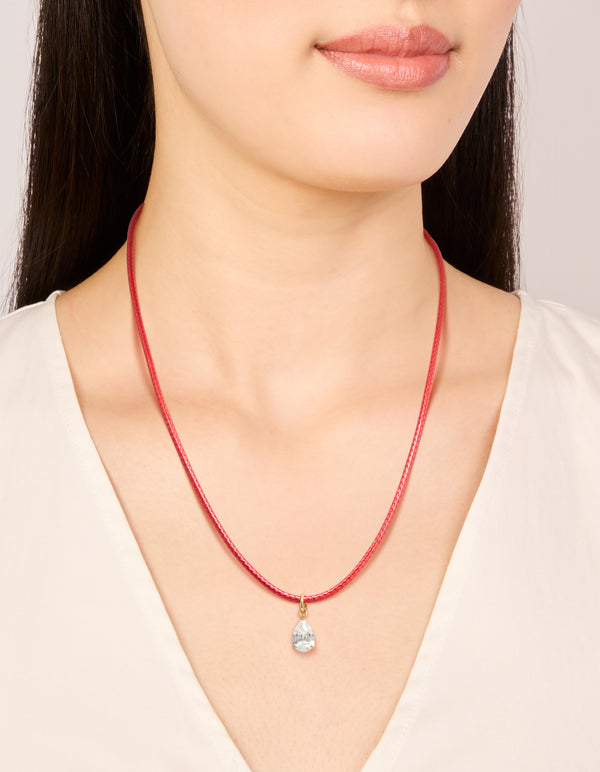 Crafted from waterproof gold plated stainless steel featuring pear cut crystal cubic zirconia pendant on red cord necklace on neck view