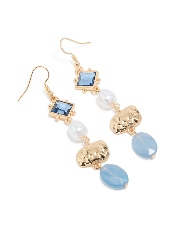 Showcasing statement drop earrings with blue beads, pearl accents, and gold organic shape charms front view
