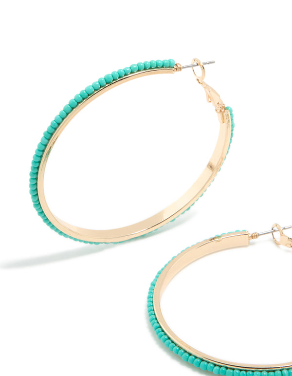 Crafted with large thin aqua beaded hoop earrings in turquoise and gold close up view
