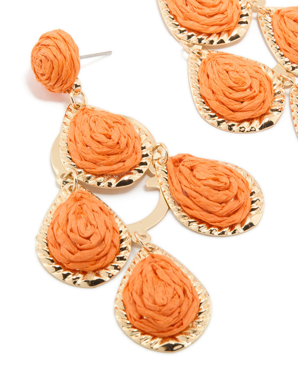 Displaying orange paper teardrop earrings in coral with statement gold detailing close up view