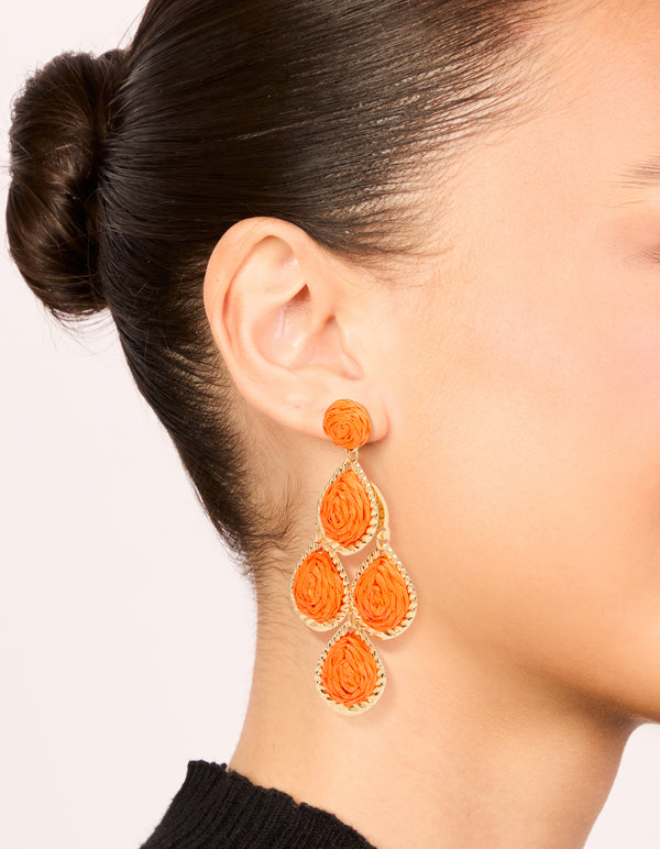 Showcasing orange paper teardrop earrings with statement styling and gold accents on ear view