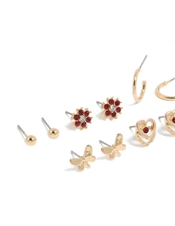 Explore stud earrings in a 7-pack with butterfly, floral, heart, and ball details featuring gold finish and red diamante accents close up view