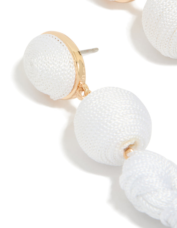 Elegantly designed white fabric tassel drop earrings with statement style and gold accents close up view
