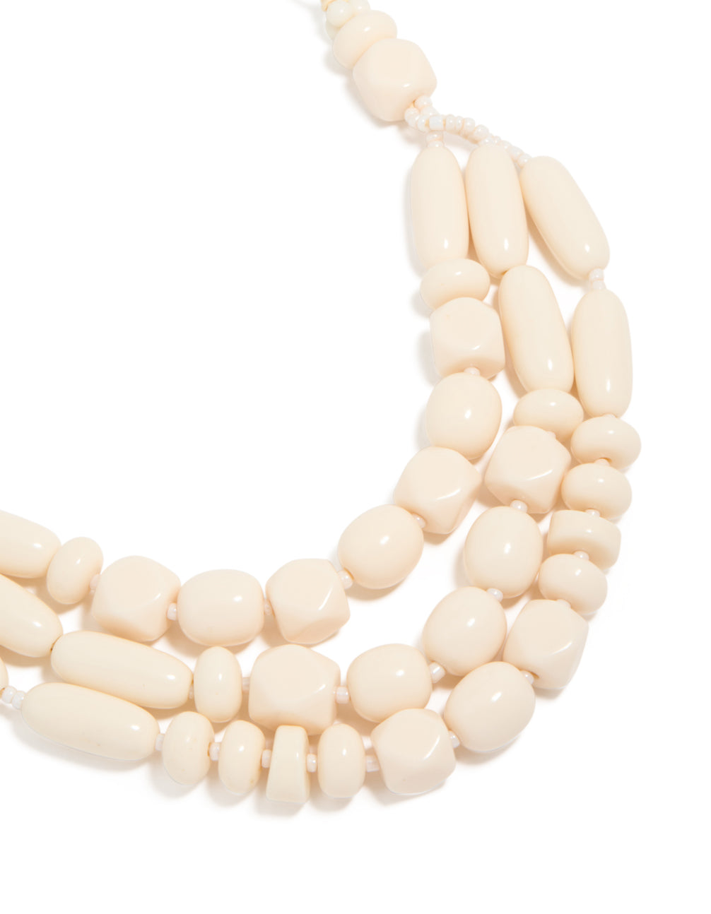 Showcasing a beaded acrylic yarn necklace in cream and gold tones close up view