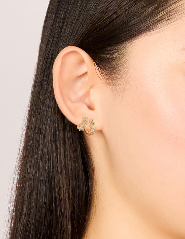 Featuring gold plated cluster cubic zirconia huggie earrings in a 2-pack with huggie closure on ear view