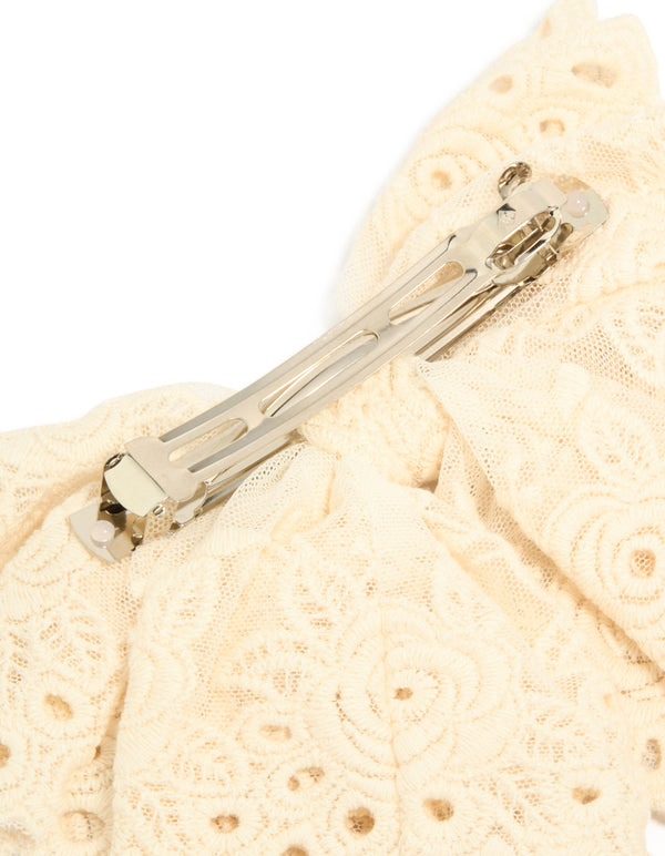 Close-up of cream broderie triple layered fabric bow hair clip showing metal clasp detail view