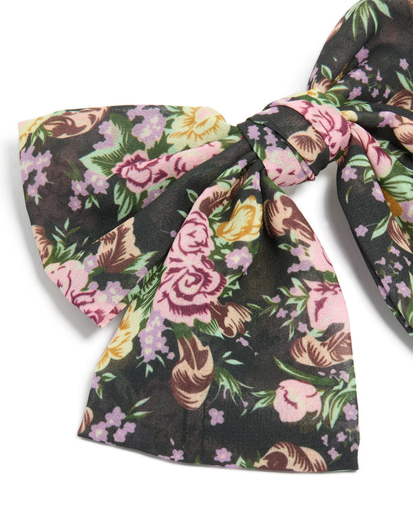 Highlighting a large bow clip with printed flowers in black, pink and green statement style detail view