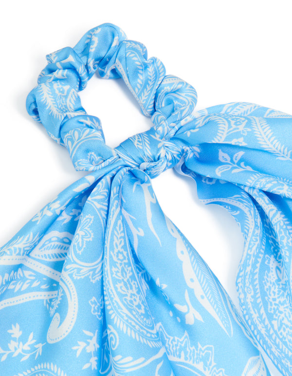 Highlighting a light blue paisley printed fabric scarf scrunchie with leaf accents in white side view