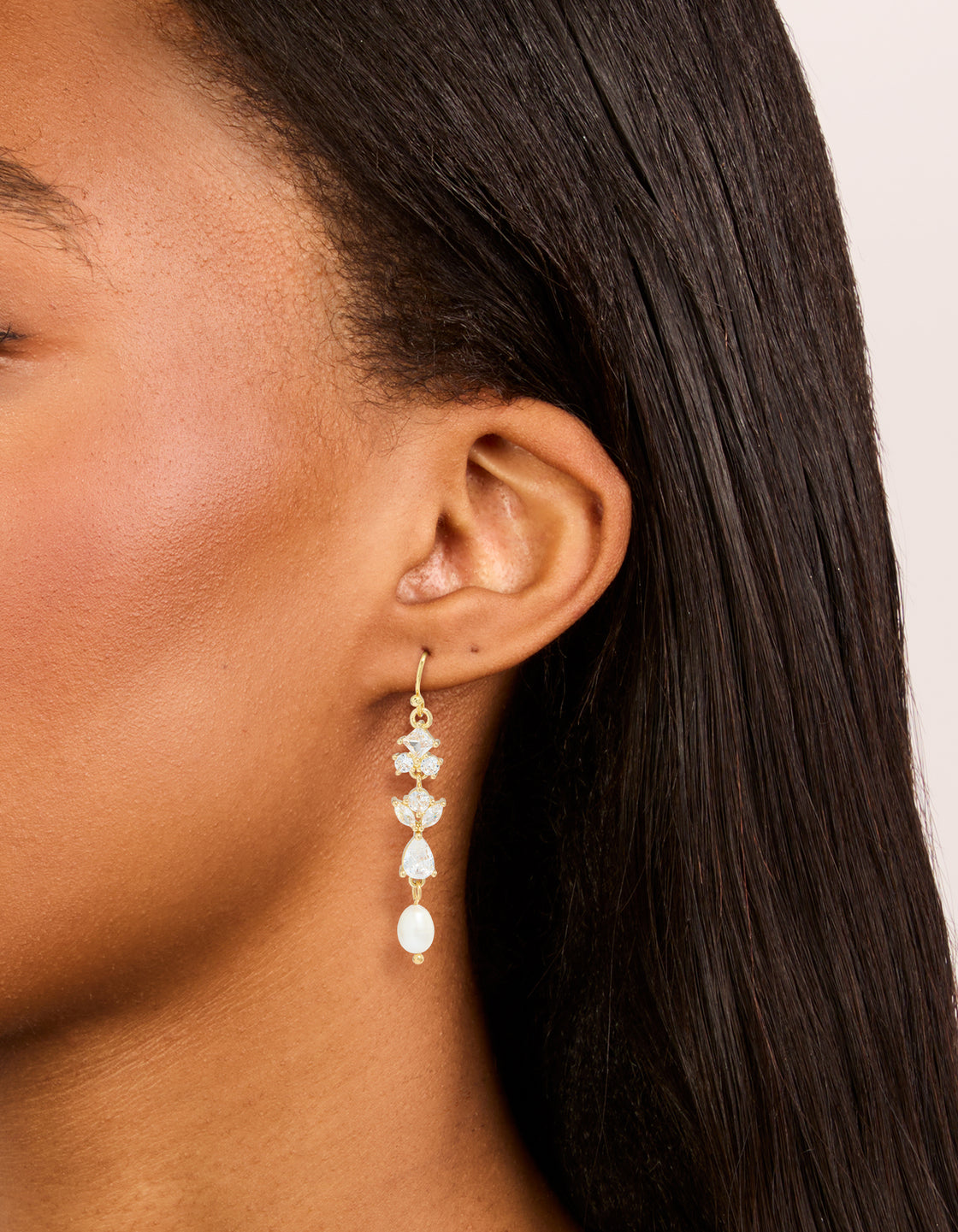 Crafted from gold plated cubic zirconia and freshwater pearl vine hook drop earrings on ear view