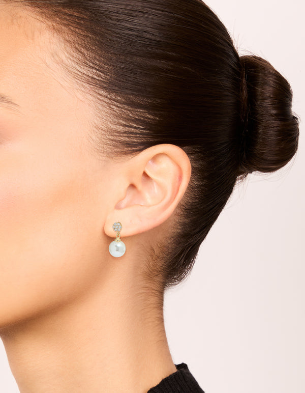 Elegant gold plated small round cubic zirconia and pearl drop earrings in white on ear view