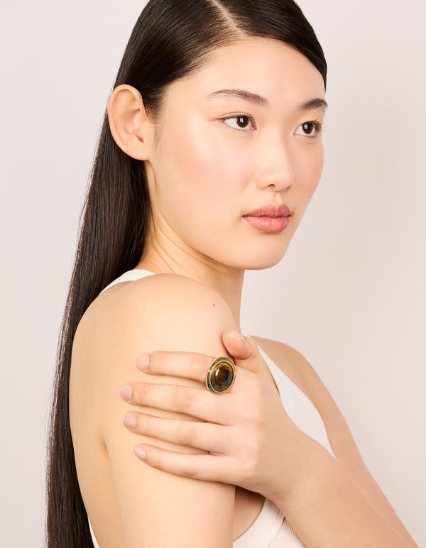 Crafted from gold plated metal, this brown stone and black enamel ring features a statement design on finger view