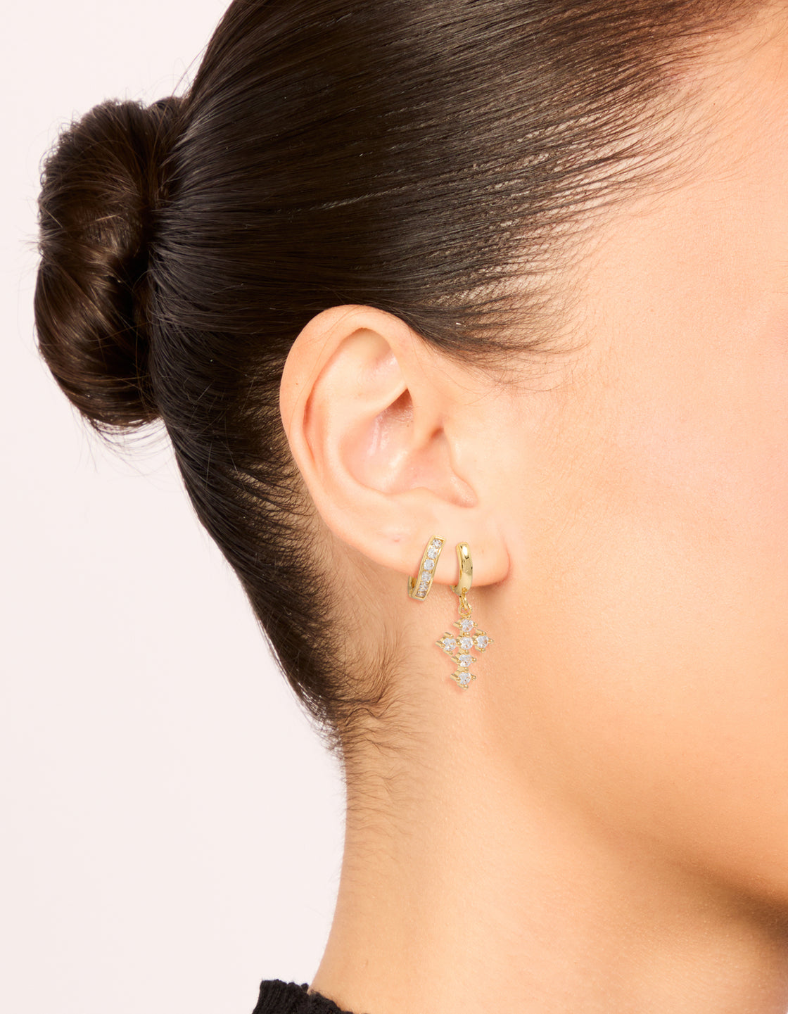 Beautifully crafted gold plated brass huggie earrings with cubic zirconia and cross in a 2-pack on ear view