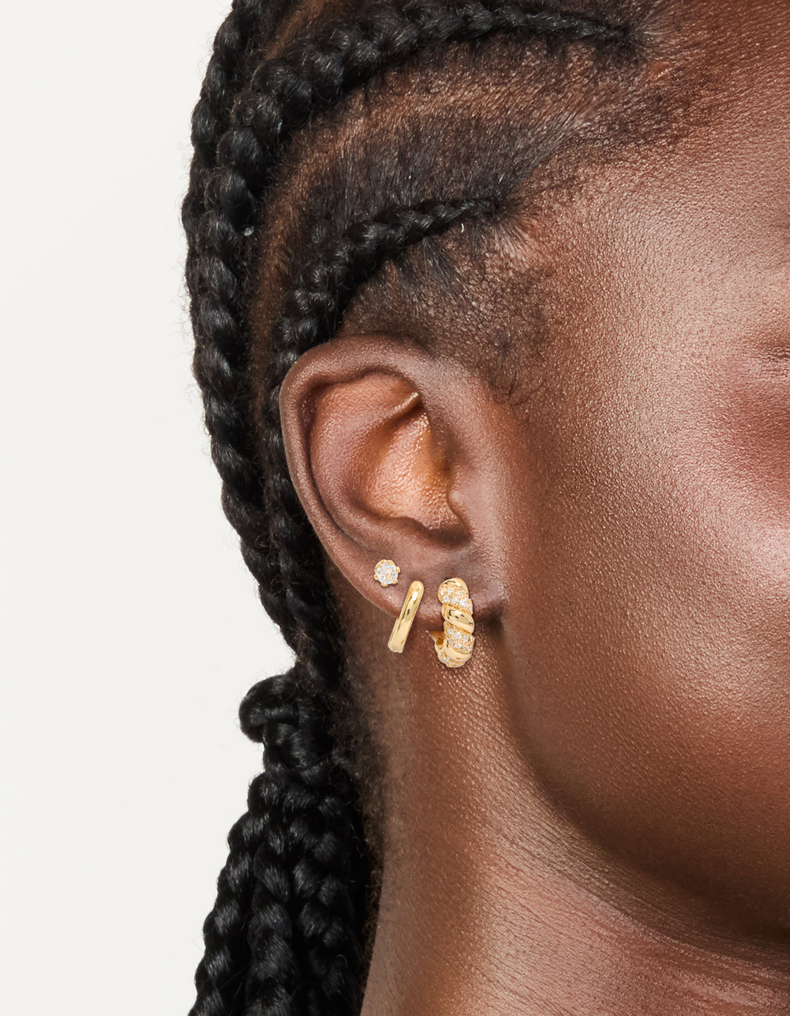 Featuring gold plated cubic zirconia twist mini huggie and stud earrings 3-pack with crystal details on ear view