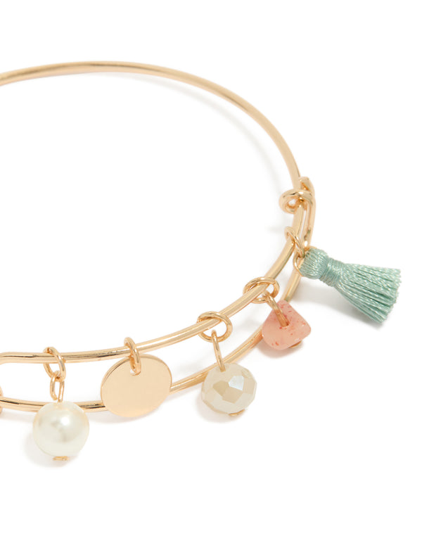 Crafted from gold, this pearl, tassel, charm bangle with beads and disc in aquamarine, and pink close up view