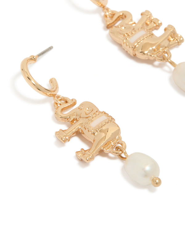 Highlighting gold hoop earrings featuring a freshwater pearl and an animal elephant charm with ivory accents close up view