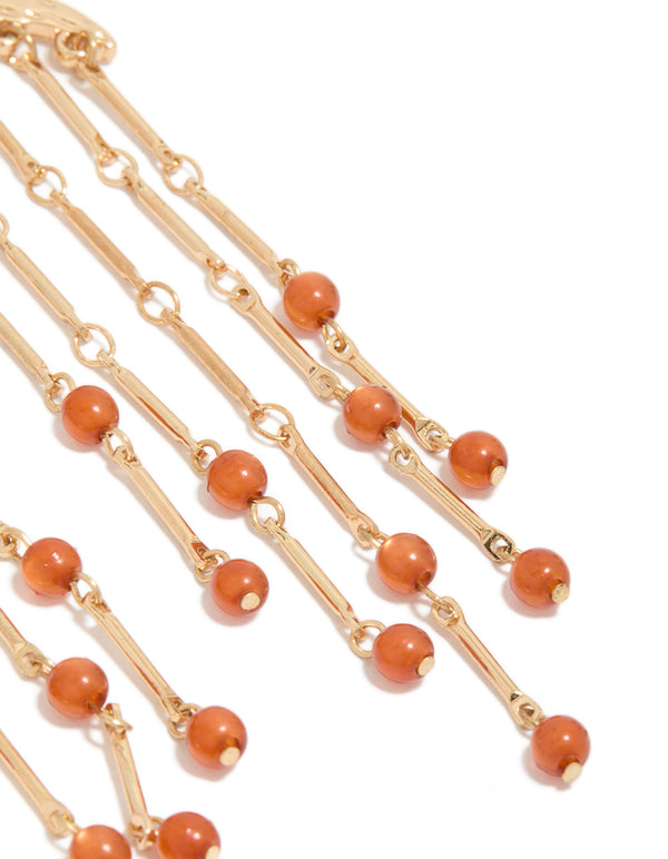 Featuring statement style, these gold cat eye stone drop earrings showcase beads accents, and charm details in coral and orange close up view