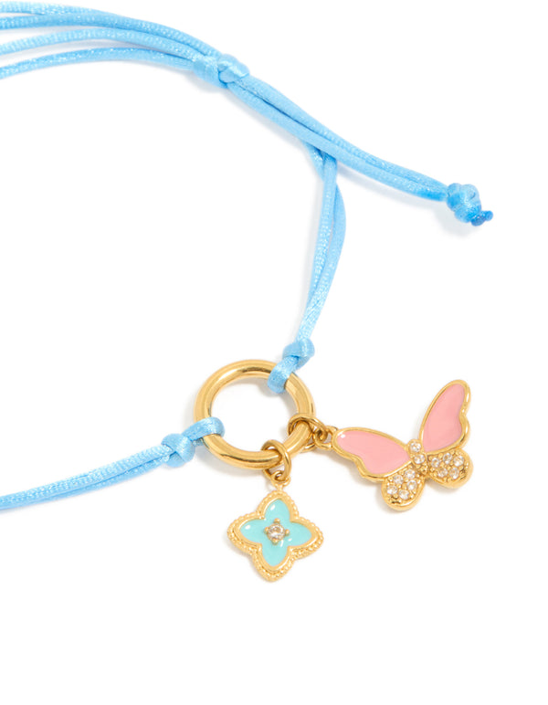 Featuring a blue cord bracelet with butterfly and floral charms crafted from gold plated stainless steel showcasing waterproof enamel in pink and aqua tones close up view