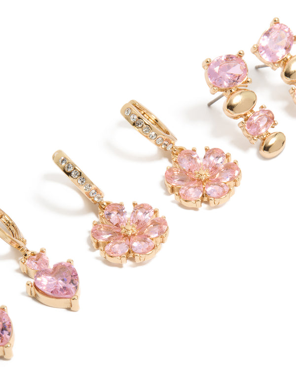 Showcasing gold pink diamante flower and heart huggie earrings in a 3-pack with oval stone cut close up view