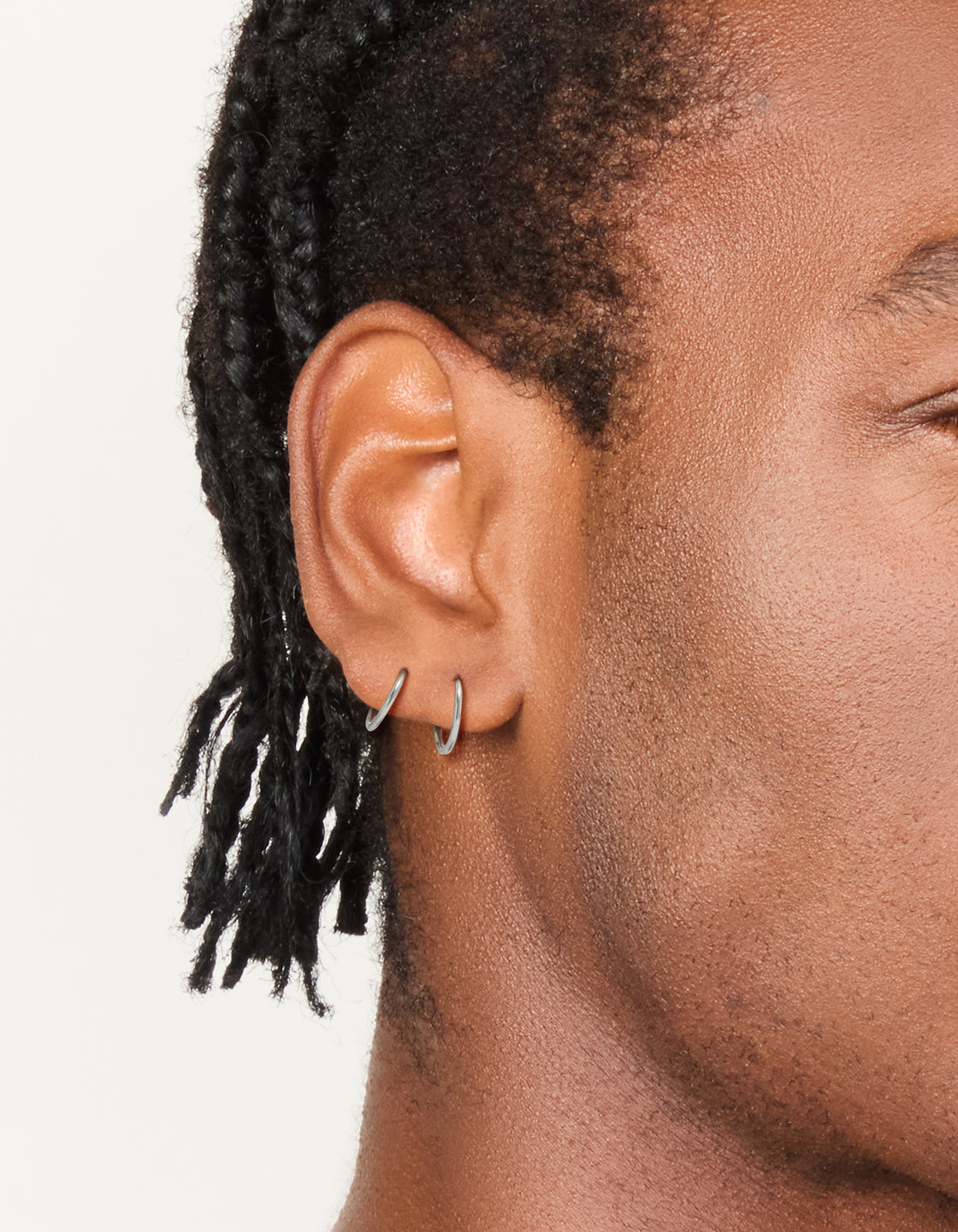 Featuring mens waterproof stainless steel mixed size sleeper earrings in a 2-pack with silver finish on ear view