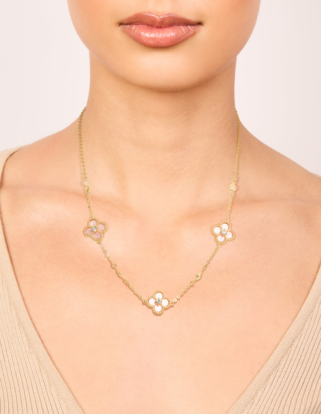 Showcasing a gold plated pink cubic zirconia flower trio necklace with floral in statement style on neck view