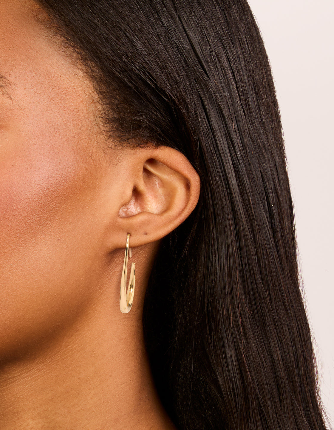 Showcasing gold plain oval hoop earrings with closure on ear view