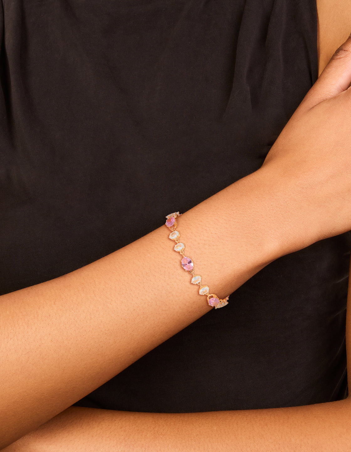 Featuring a bracelet with round stone cut in gold, pink and clear diamantes on wrist view