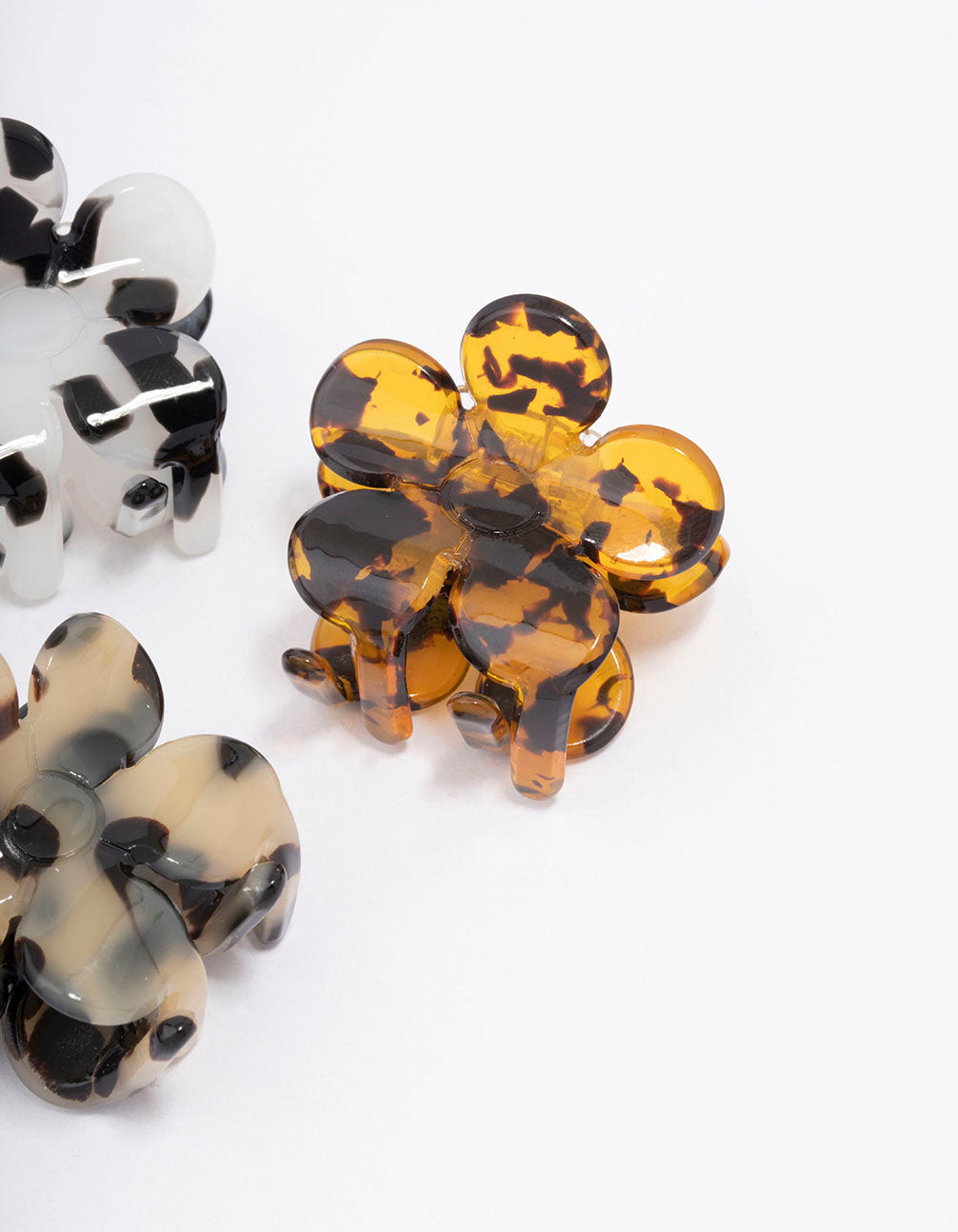 Featuring small daisy hair claw clip 3-pack with floral design in tortoiseshell pattern showcasing black, white, orange, and beige detail view