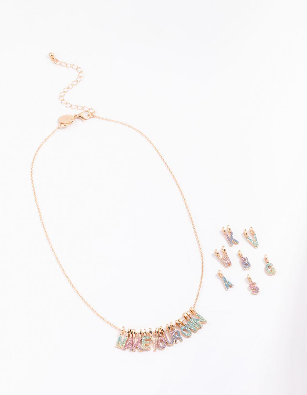 Presenting a kids gold make your own DIY rainbow glitter charm necklace kit with initials in pink aqua and lavender front view