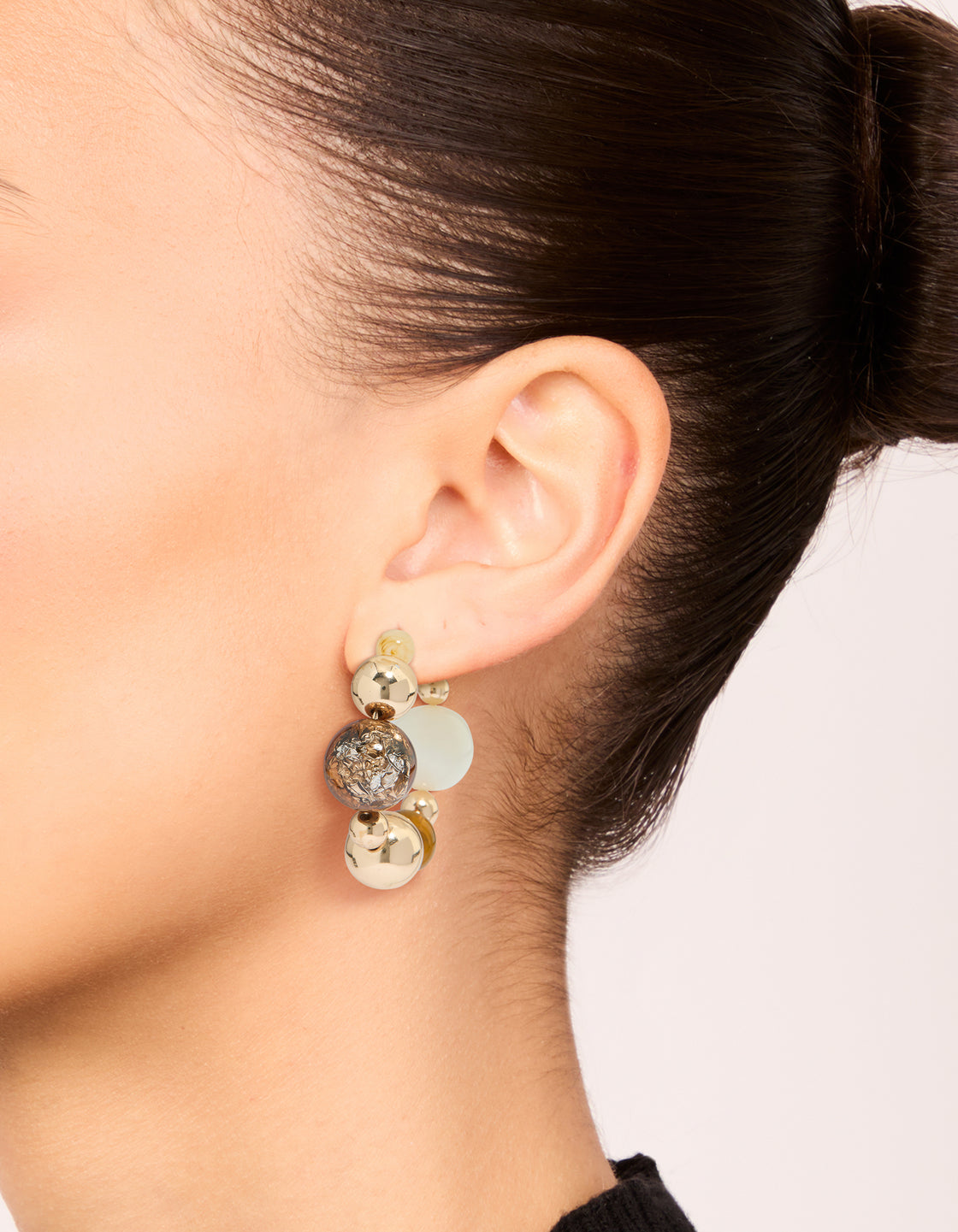 Showcasing chunky beaded ball hoop earrings in gold with neutral tones on ear view