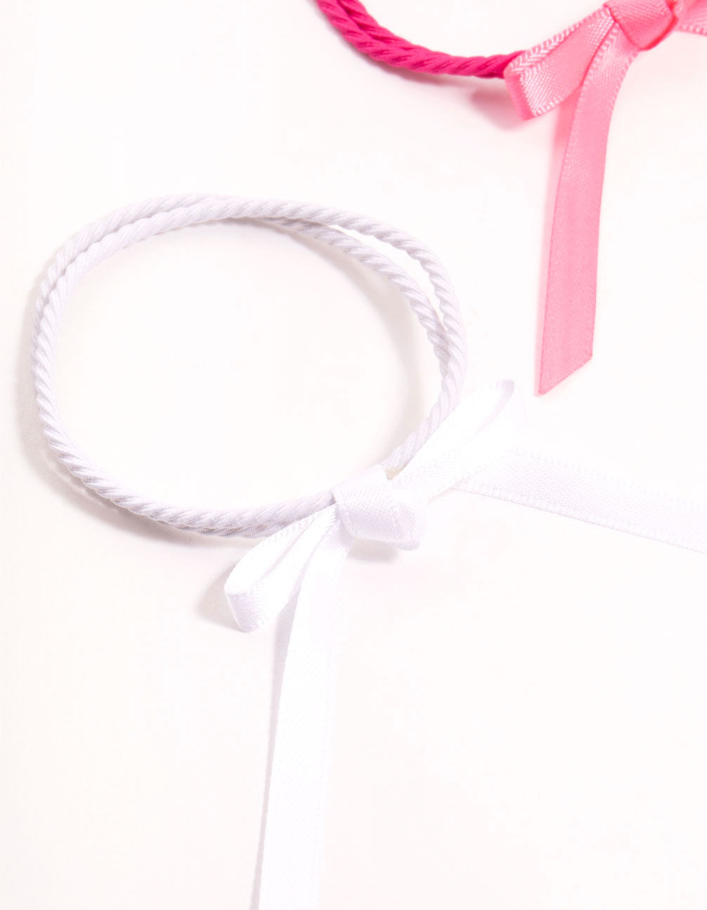Featuring thin fabric bow hair ties in a 4-pack with solid pink, white, hot pink, and coral tones detail view