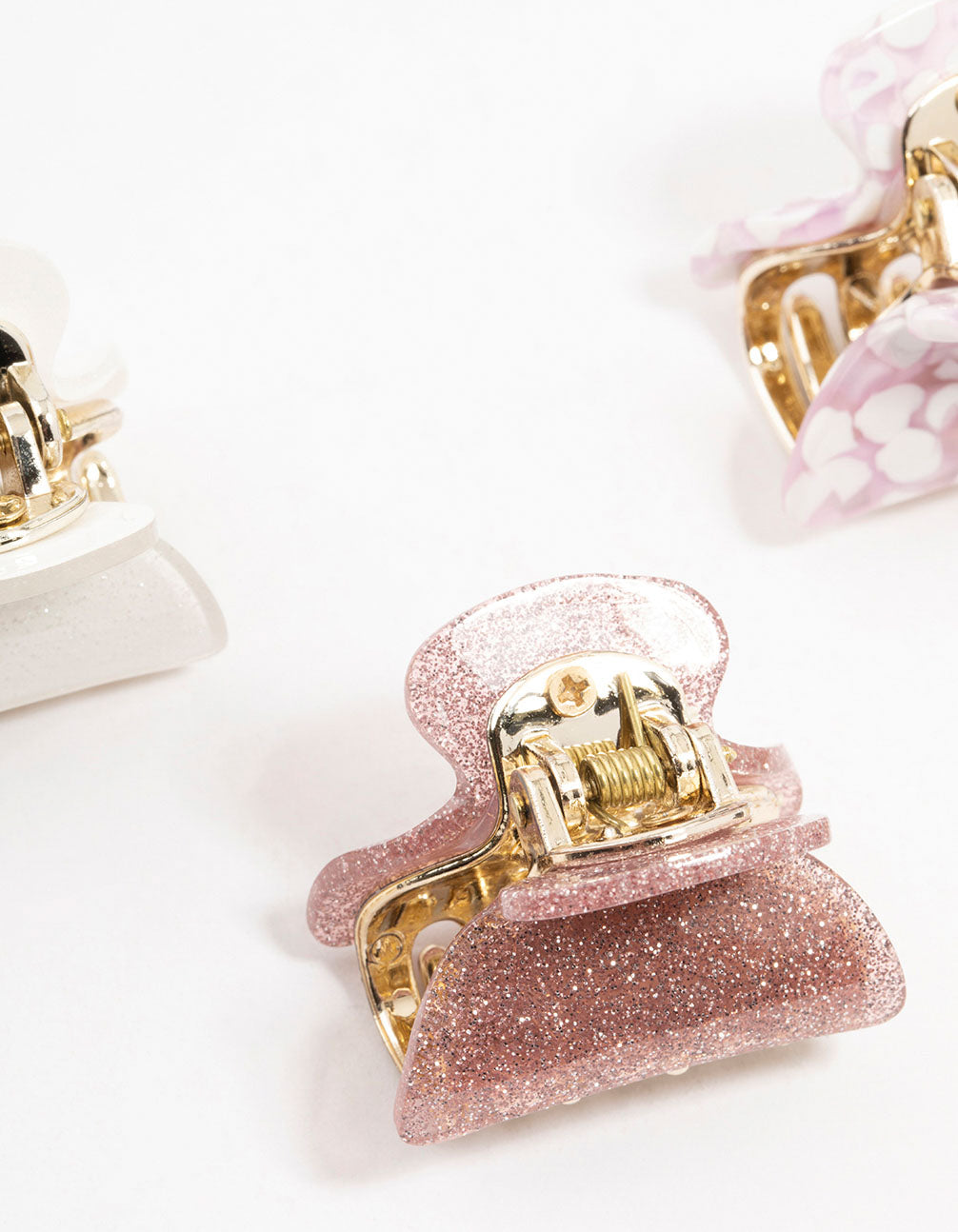 Shop acrylic claw clips with glitter in light pink, white, gold, and rosy brown detail view