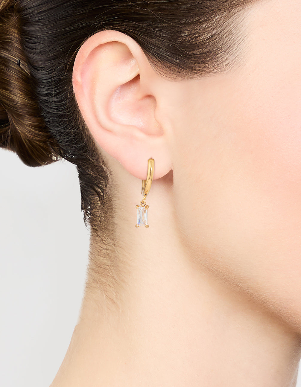 Showcasing waterproof gold plated stainless steel baguette diamante huggie earrings on ear view