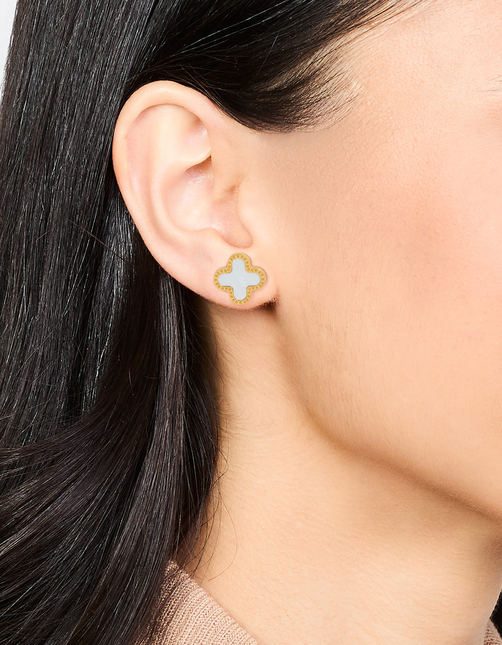 Featuring waterproof stainless steel stud earrings with floral enamel design in gold plated finish on ear view