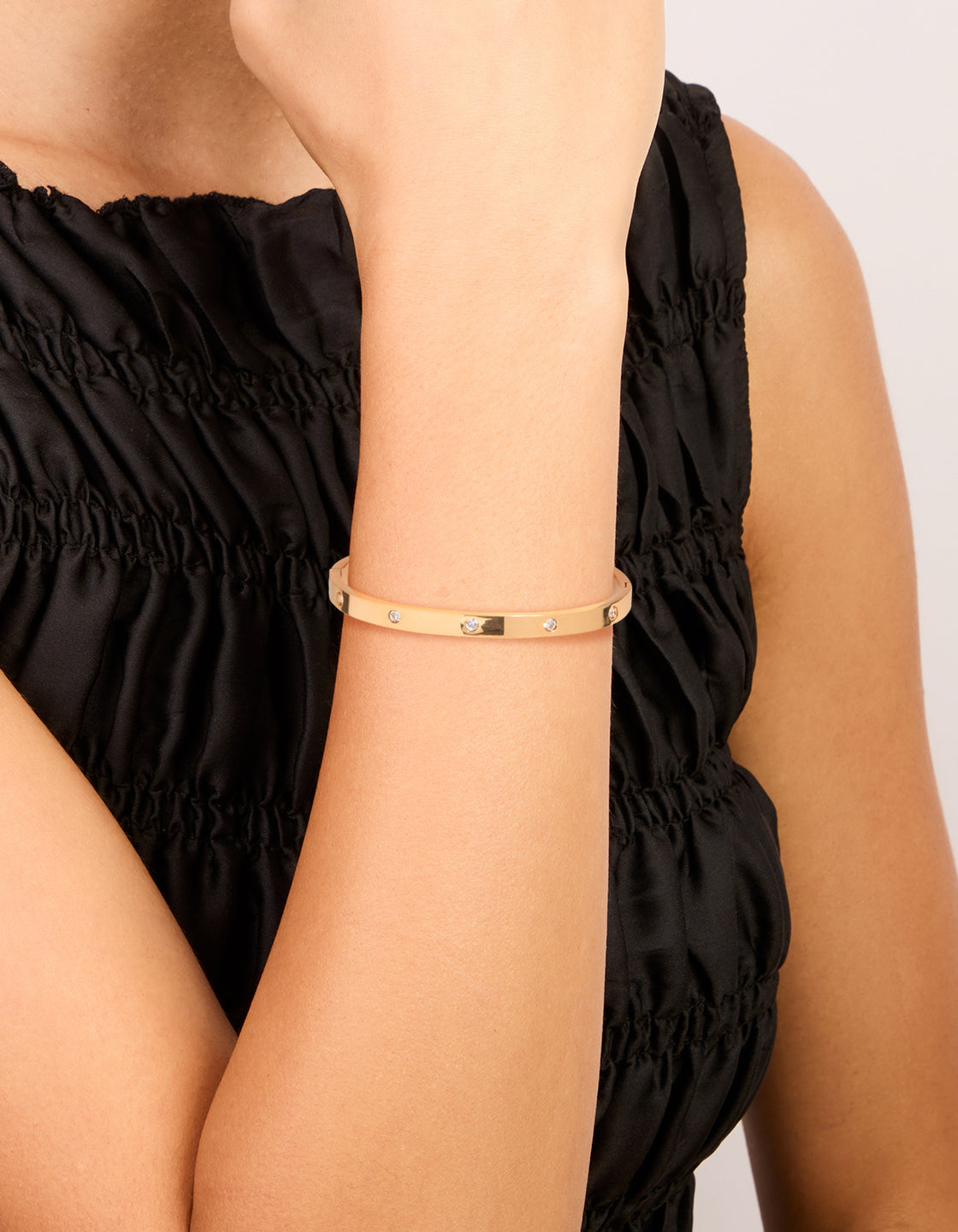 Showcasing a waterproof statement gold plated stainless steel diamante hinged bangle on wrist view