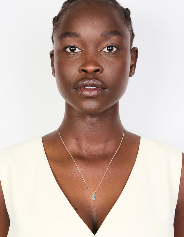This sterling silver blue cubic zirconia and starfish pendant necklace features ocean charm details in delicate crystal design on model view