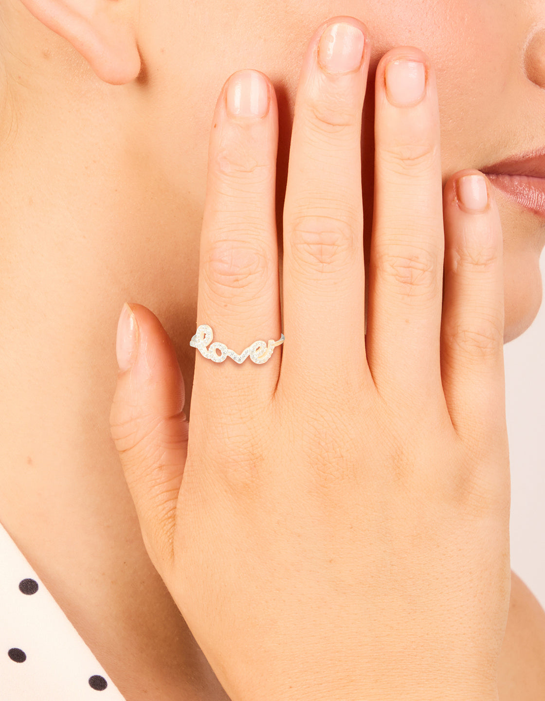 Showcasing a sterling silver cubic zirconia love ring with script detailing and statement style in clear stone on finger view