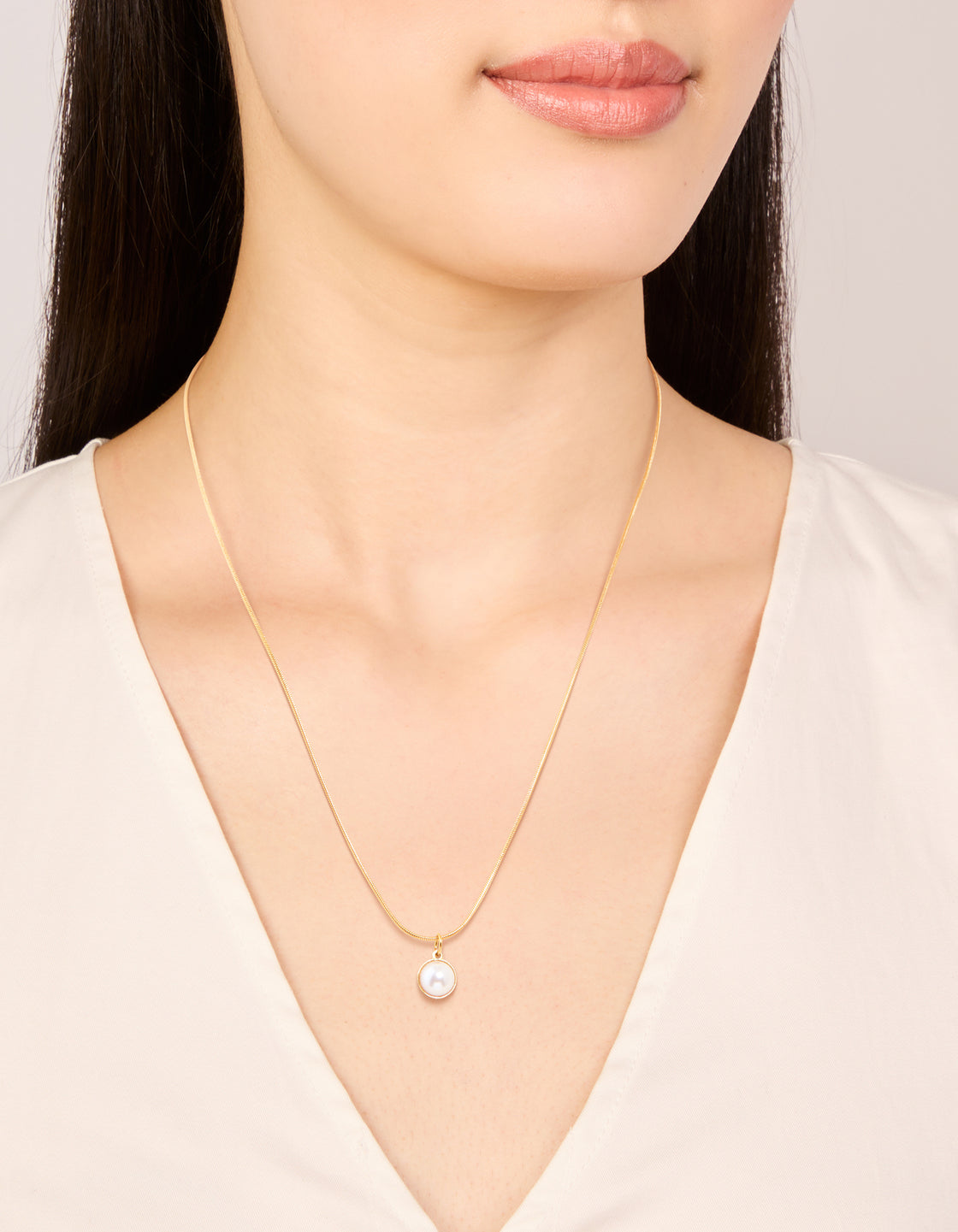 Showcasing a waterproof pendant necklace crafted from stainless steel with freshwater pearl in gold plated finish on neck view