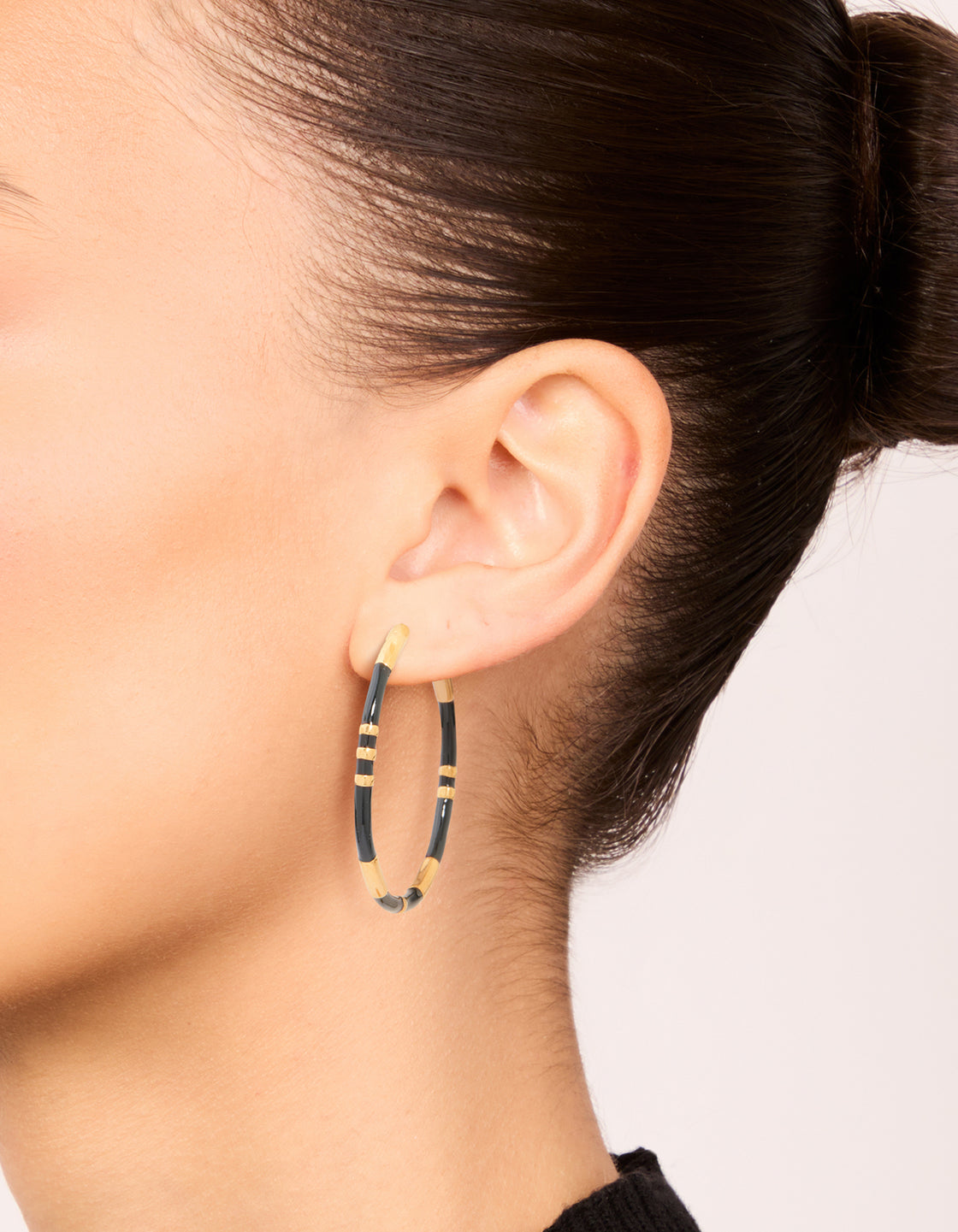 Featuring waterproof gold plated stainless steel black enamel striped hoop earrings on ear view