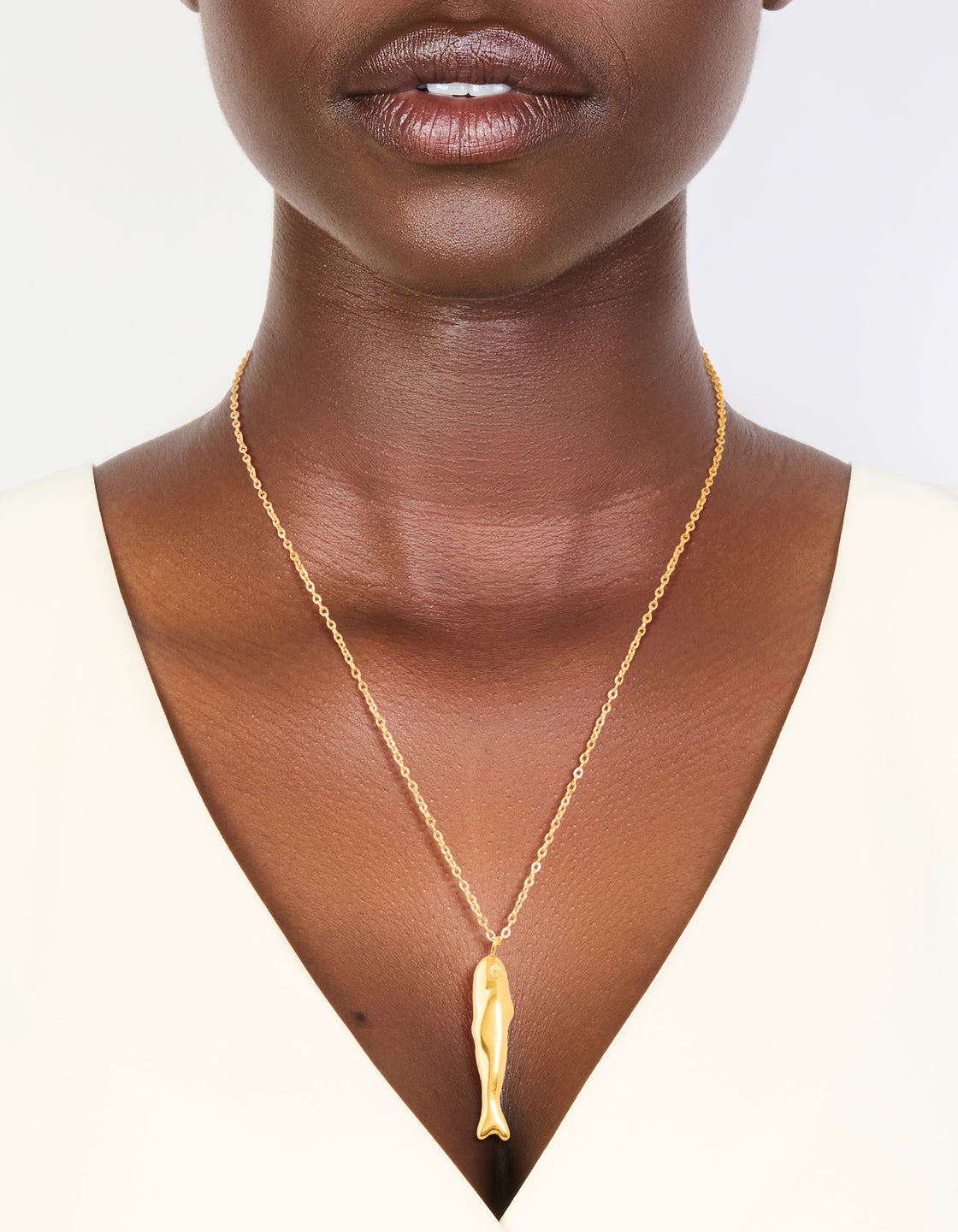 Crafted from waterproof stainless steel, this gold plated sardine pendant necklace features ocean-inspired design on neck view
