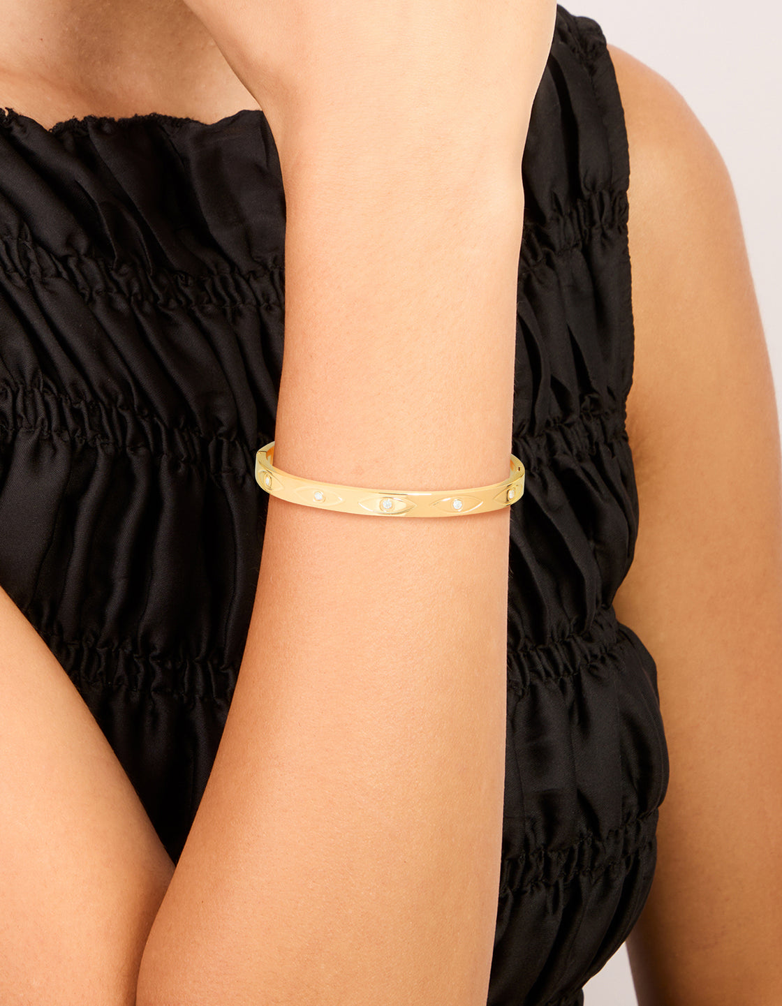 Showcasing a gold plated stainless steel evil eye bangle with cubic zirconia in a statement style on wrist view