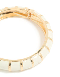 Featuring a striped pattern, this enamel bangle in gold and ivory closure detail view - link has visual effect only