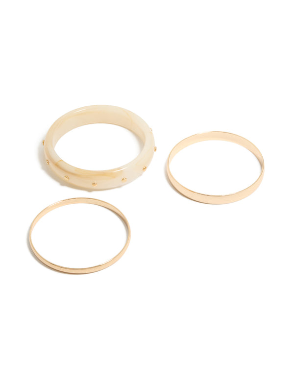 Showcasing a 3-pack of studded acrylic bangles in gold and cream tones front view