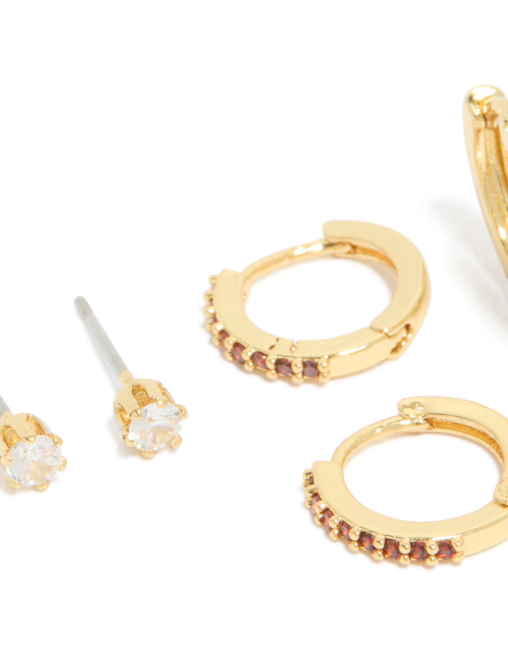 Featuring huggie stud crystal cubic zirconia garnet birthstone earrings in gold plated brass with red and clear accents close up view